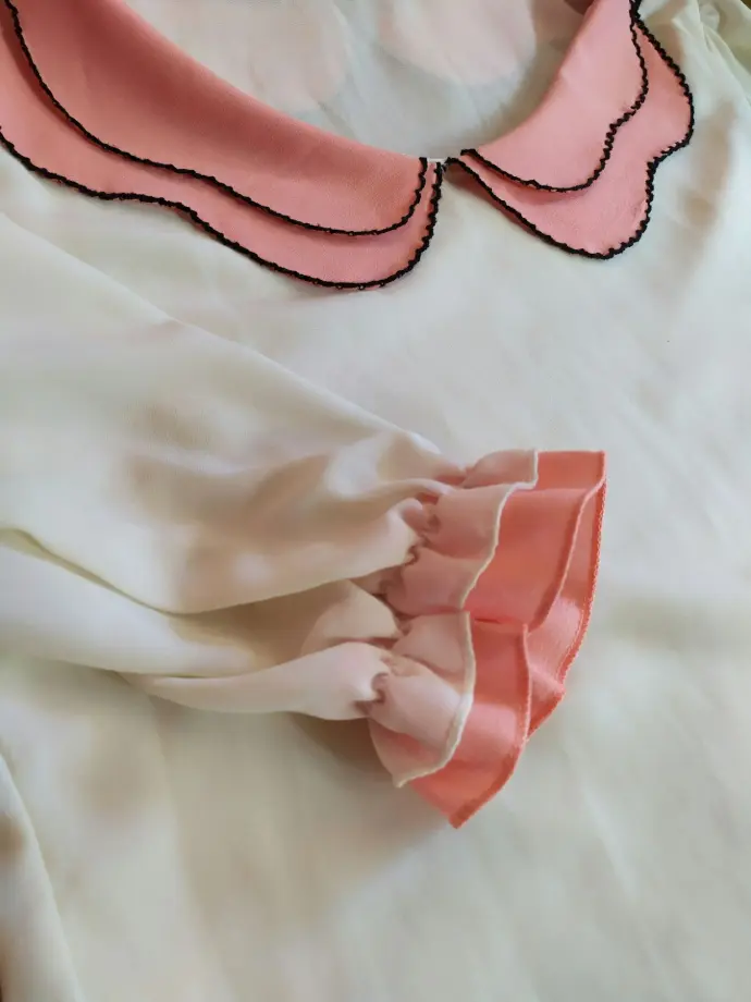 A pink and white blouse is displayed.